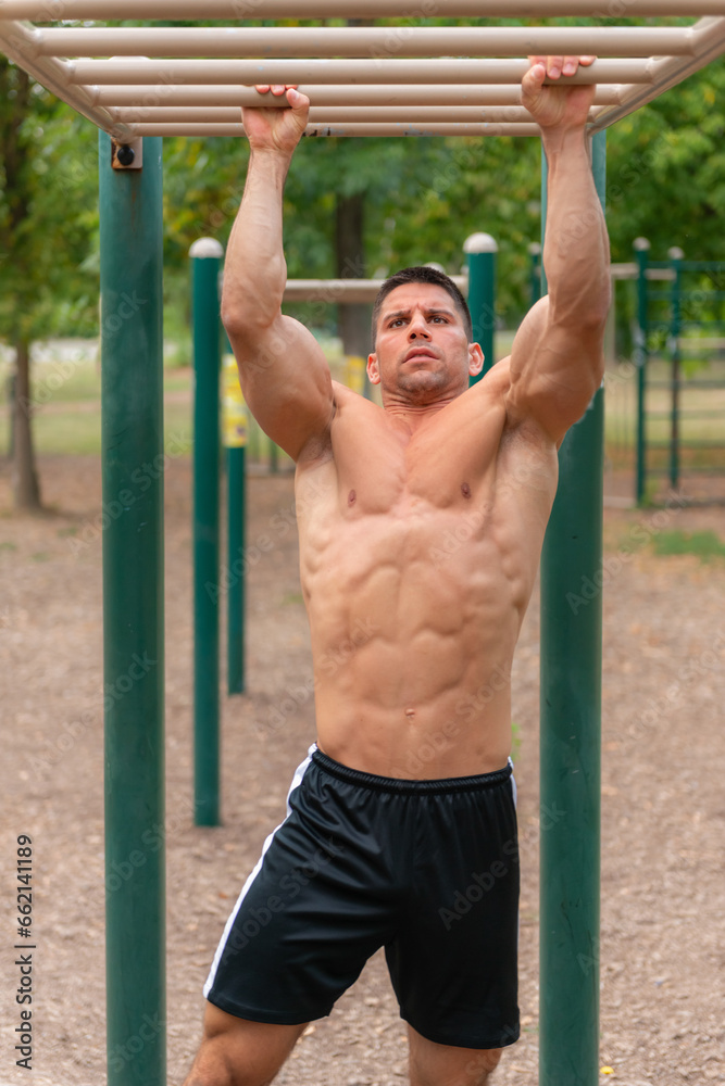 A strong man demonstrates his power while exercising on monkey bars, showcasing his fitness and strength