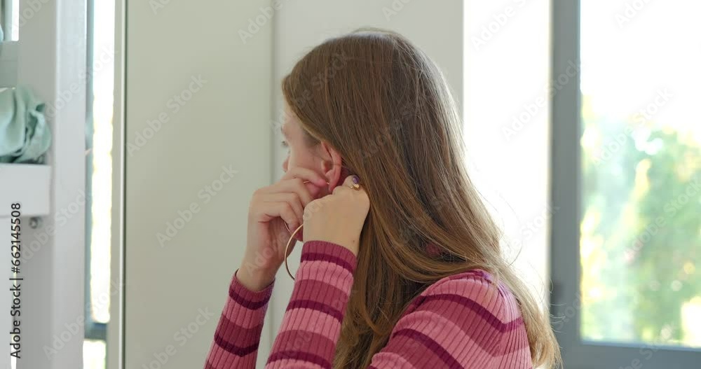 Cute young girl puts on her earrings