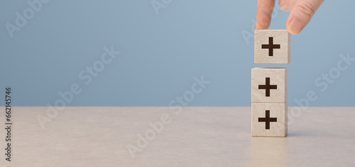 Plus sign in wooden cubes stacking. added value, benefits. Putting cubes with plus sign to offer positive things. Addition and positive mindset thinking such as profit, benefits, development