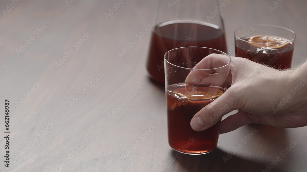 man hand take mulled wine in thin tumbler glass from walnut table man hand take mulled wine in thin tumbler glass from walnut table