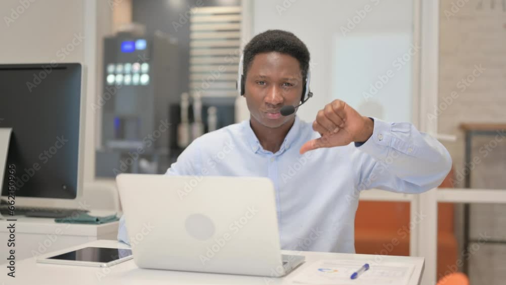 Thumbs Down by African Man with Headset Using Laptop in Call Center Thumbs Down by African Man with Headset Using Laptop in Call Center