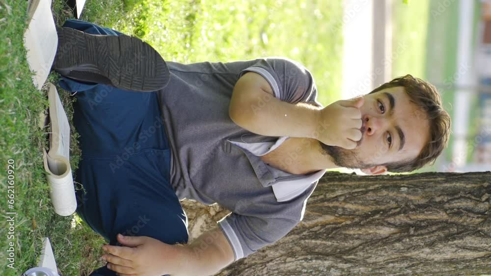 Vertical Video of University dwarf student studying outdoors biting his nails from stress. Vertical Video of University dwarf student studying outdoors biting his nails from stress.