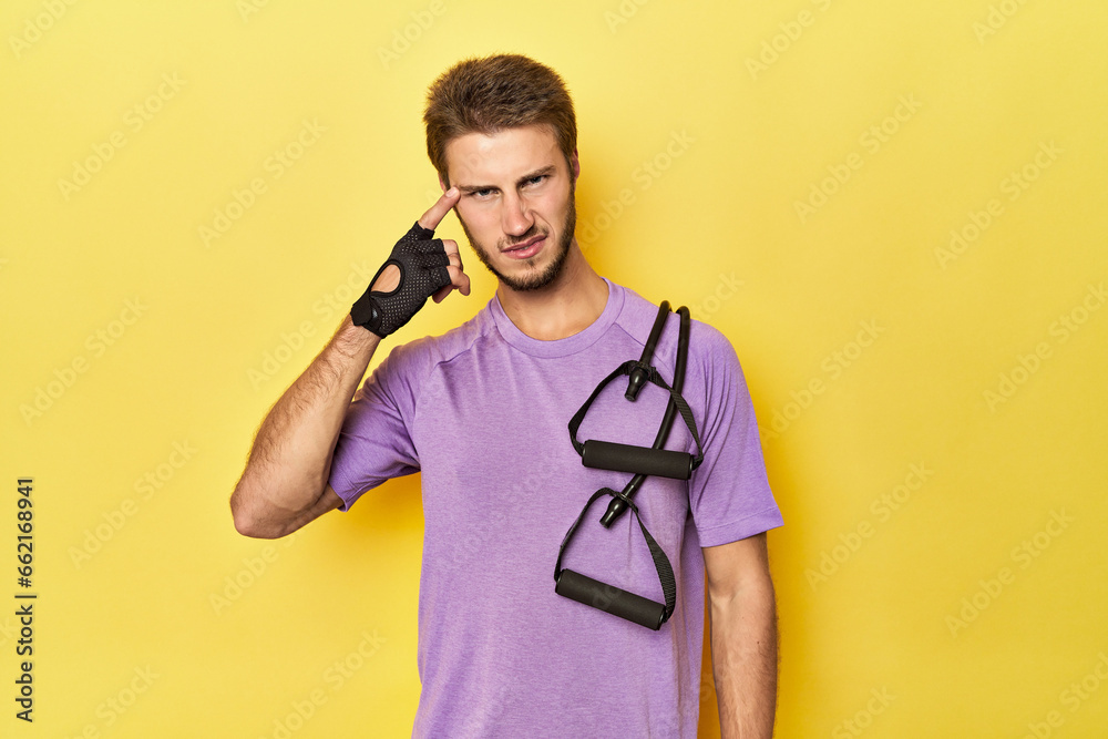 Athlete with resistance band on yellow showing a disappointment gesture with forefinger. Athlete with resistance band on yellow showing a disappointment gesture with forefinger.