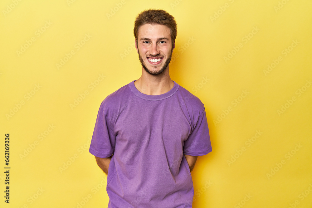 Young Caucasian man on a yellow studio background happy, smiling and cheerful.