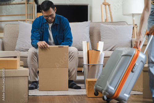 Young couple relaxing sitting on the floor around cardboard boxes at home, smiling happy moving to a new house.