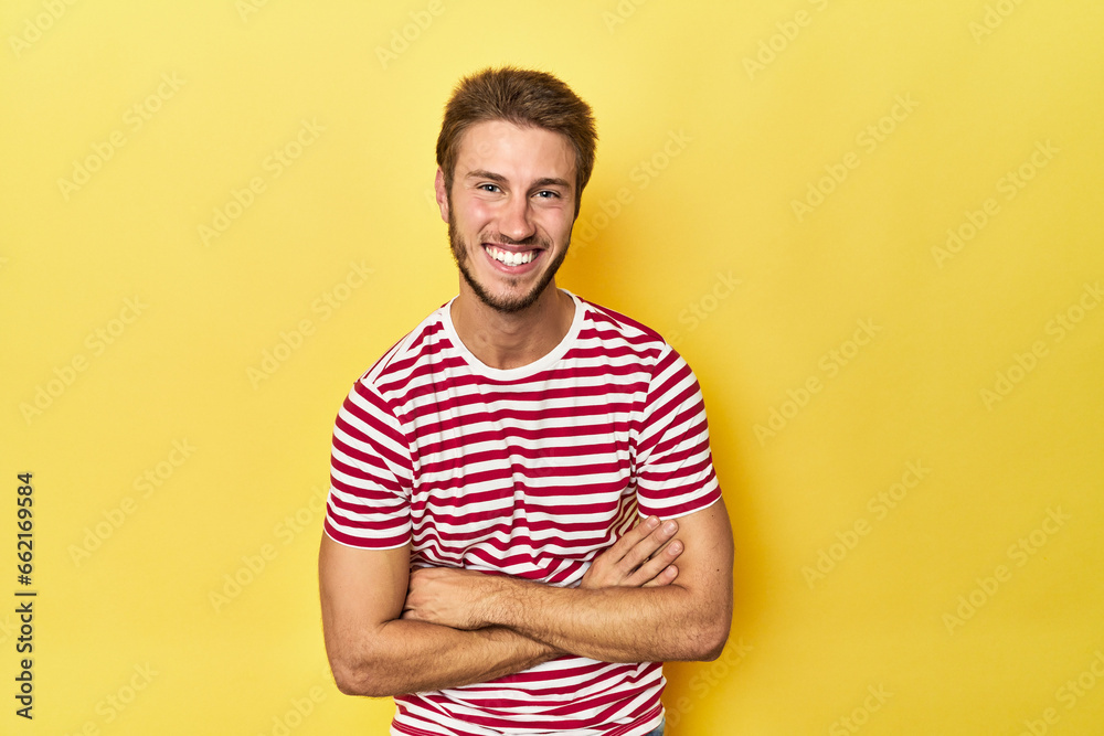 Young Caucasian man on a yellow studio background laughing and having fun. Young Caucasian man on a yellow studio background laughing and having fun.