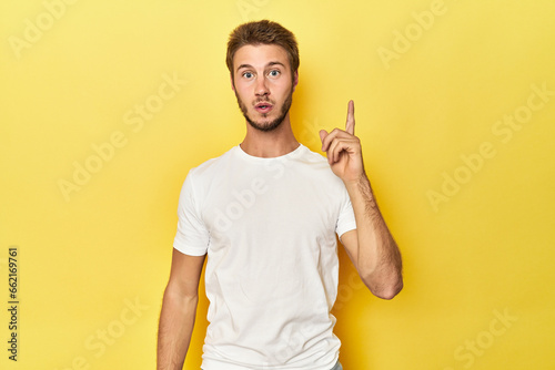 Young Caucasian man on a yellow studio background having an idea, inspiration concept.