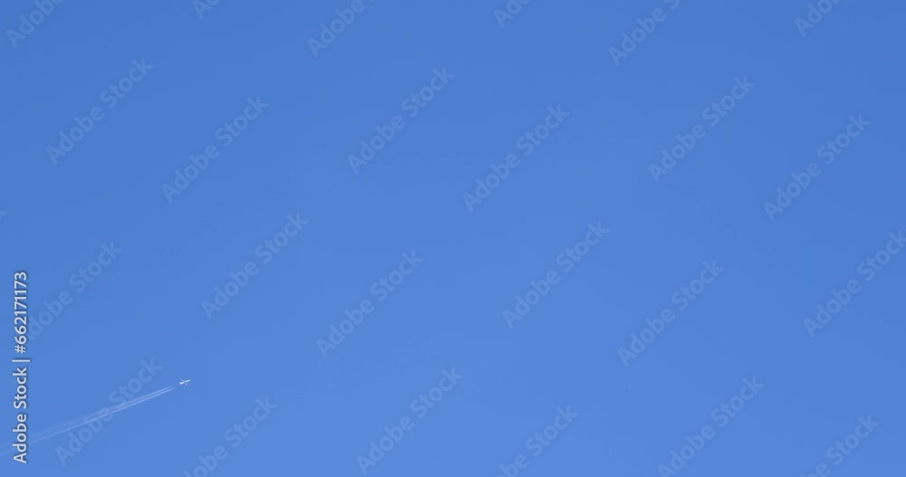 Airplane flying on deep blue sky with chemical direction trails, view from a distance Airplane flying on deep blue sky with chemical direction trails, view from a distance