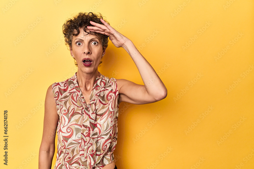 Mid-aged caucasian woman on vibrant yellow shouts loud, keeps eyes opened and hands tense. Mid-aged caucasian woman on vibrant yellow shouts loud, keeps eyes opened and hands tense.