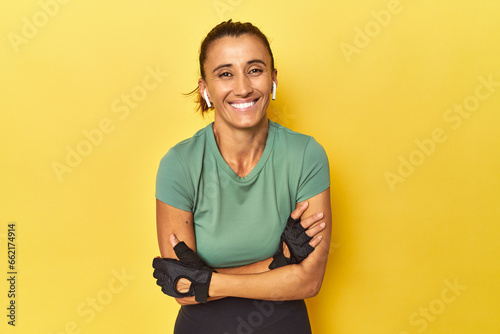 Athletic middle-aged woman on yellow backdrop laughing and having fun. photo