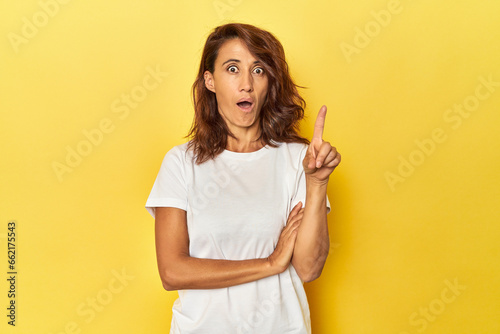 Middle-aged woman on a yellow backdrop having some great idea, concept of creativity.