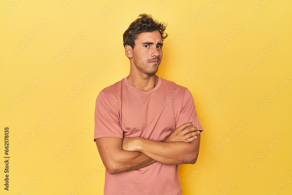Young Latino man posing on yellow background suspicious, uncertain, examining you. Young Latino man posing on yellow background suspicious, uncertain, examining you.