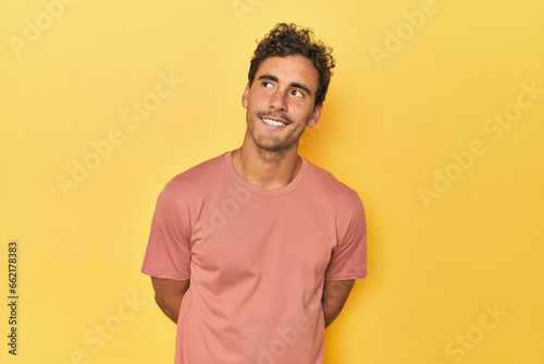 Canvastavla Young Latino man posing on yellow background relaxed and happy laughing, neck stretched showing teeth