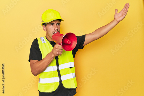 Worker in yellow shouting through megaphone on yellow.