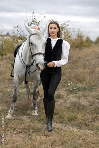 portrait of beautiful woman riding horse in orchard,touches horse muzzle, with forehead glued from animal head.girl calms horse with hand.female and anima in embrace,hugging neck,closed eyes.