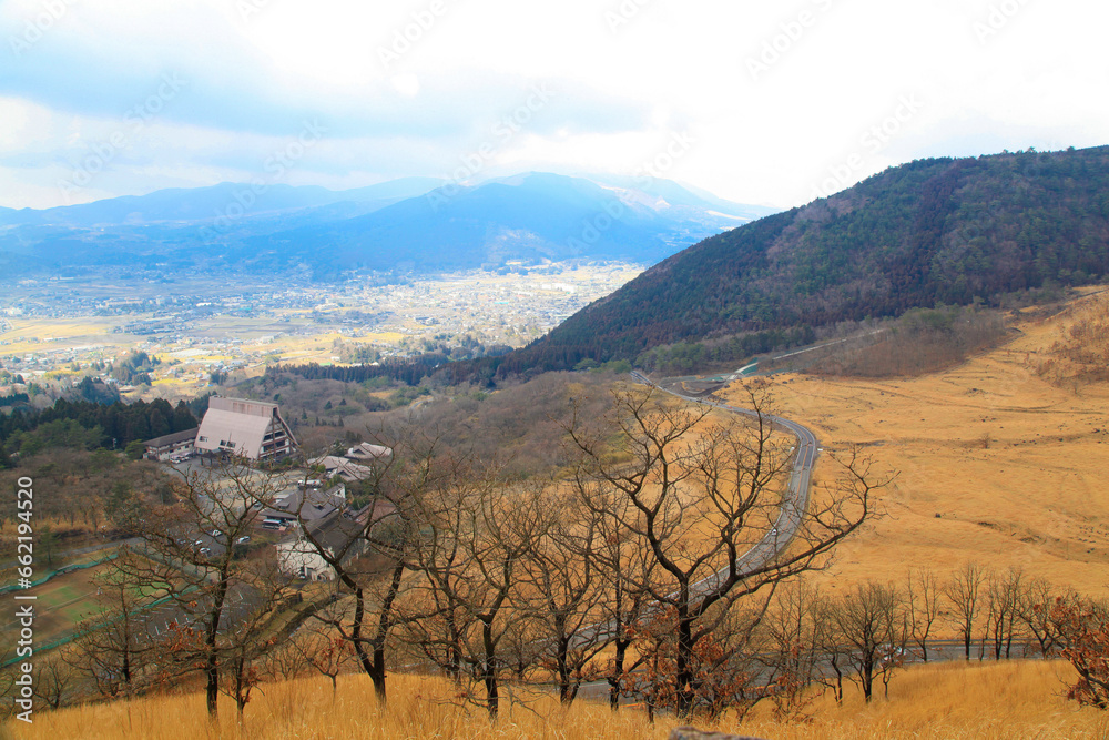 Scenery from the Aso Kuju National Park Sagiridai Overlook. You can see the lines of the winding road that climbs beautifully and beyond is a view of the village below in the valley. Oita, Japan Scenery from the Aso Kuju National Park Sagiridai Overlook. You can see the lines of the winding road that climbs beautifully and beyond is a view of the village below in the valley. Oita, Japan