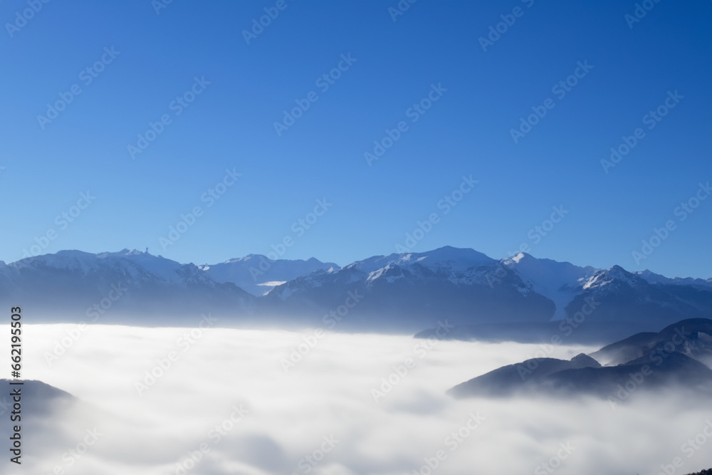 landscape of blue sky with high mountains protruding through the white thick fog. AI GENERATE