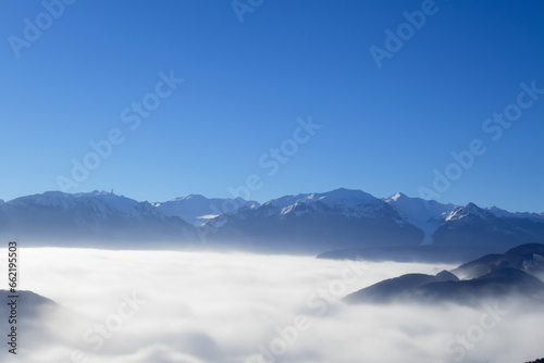landscape of blue sky with high mountains protruding through the white thick fog. AI GENERATE © ibragimova