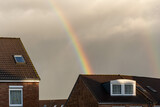 rainbow over roof of a house, cloudy sky