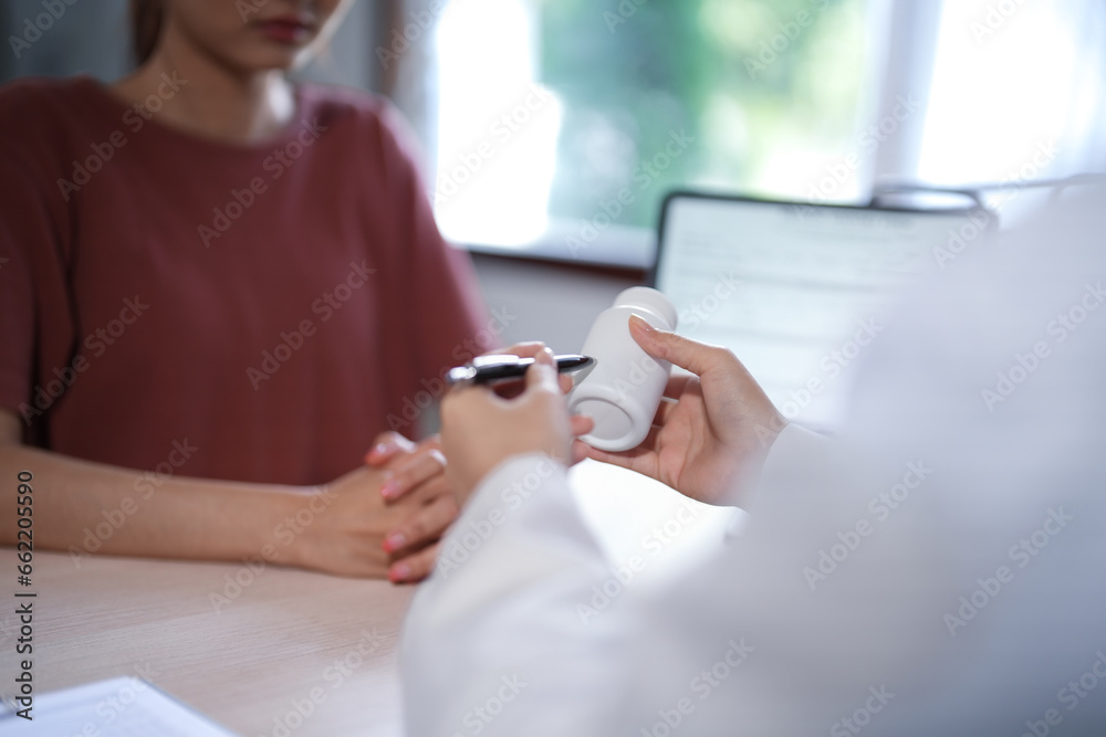 Asian psychologist women showing pills bottle to explaining medicine and prescription to female patient while giving counseling to explaining about mental health therapy to female patient in clinic