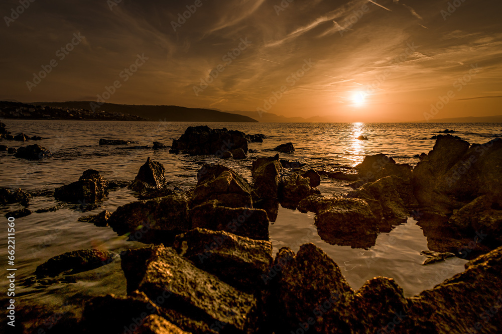 Obraz premium Wschód słońca nad brzegiem morza. Brzeg morza i wschód słońca na plaży. Wschód słońca nad kamienistą plażą w Chorwacji w okolicach Splitu. Split i wschód słońca. Słońce nad morzem. 