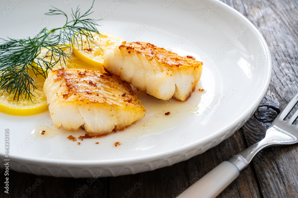 Seared cod loin and sliced lemon on wooden table
Seared cod loin and sliced lemon on wooden table
