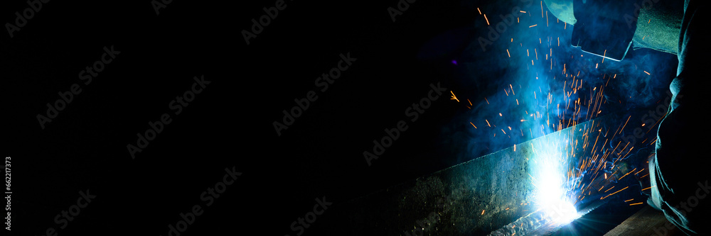 Welder uses torch to make sparks during manufacture of metal equipment - obrazy, fototapety, plakaty 