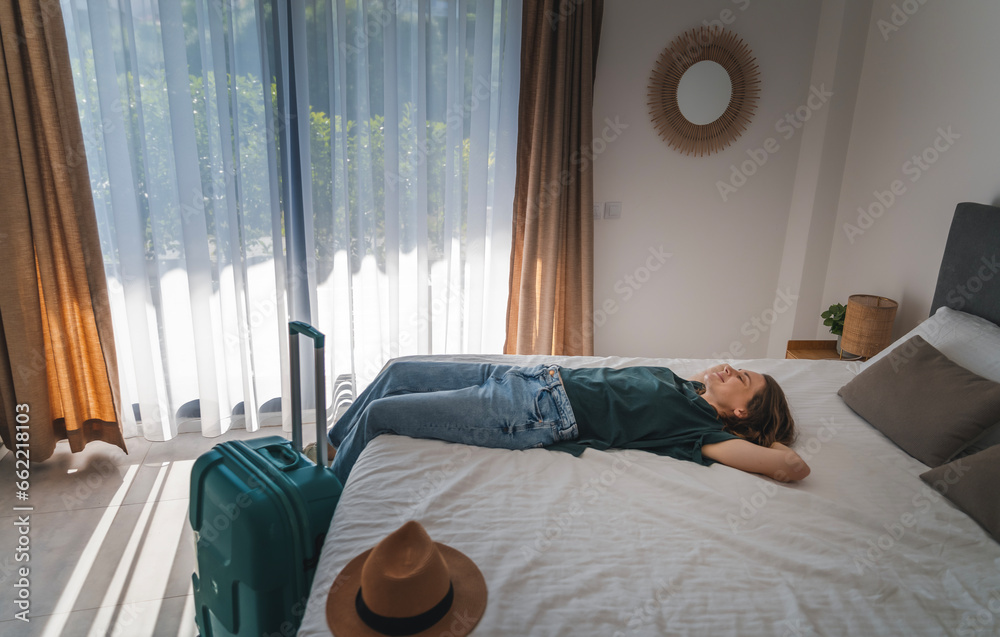 Young woman lying on the bed in a hotel room. Booking and Accommodation travel concept