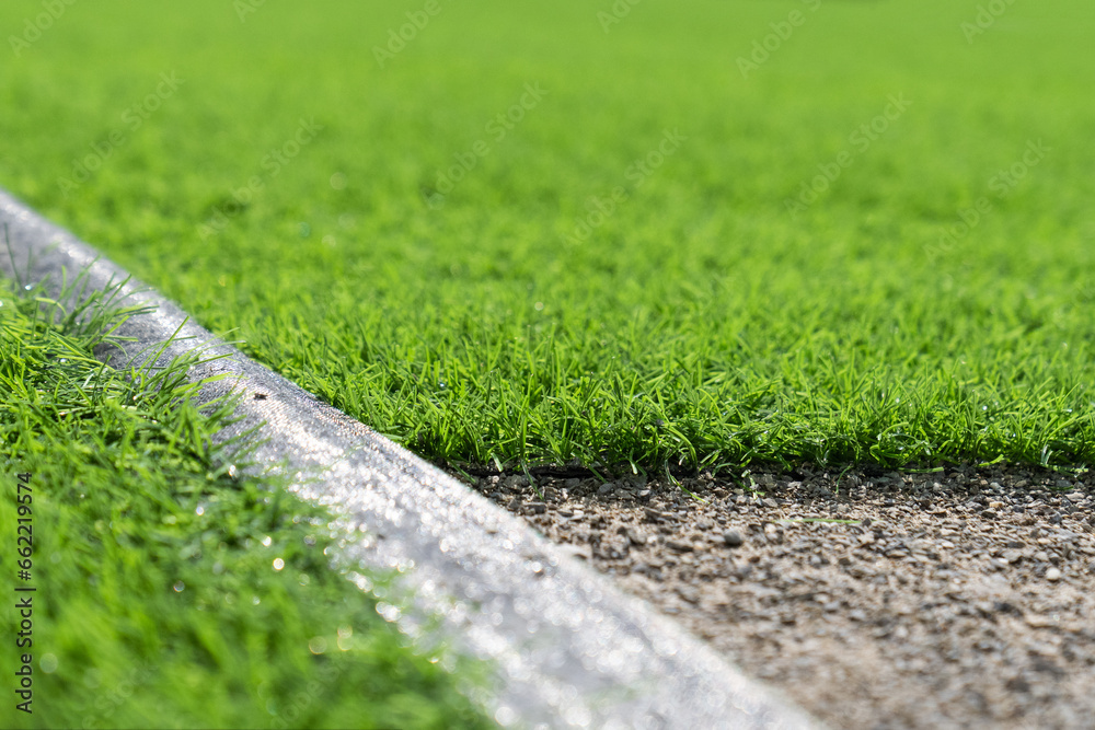 Evergreen artificial grass close-up. Short cut real grass on the edge of the pitch in the stadium. Artificial grass close-up. Artificial turf background. 
