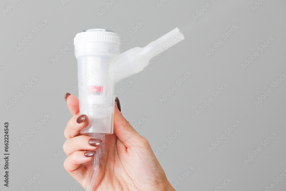 Nebulizator in hand background. Nebulizer isolated. Medical device background. Woman hand holding nebulizator. Lungs and throat treatment. Mouth inhaler. Nebulizator in hand background. Nebulizer isolated. Medical device background. Woman hand holding nebulizator. Lungs and throat treatment. Mouth inhaler.