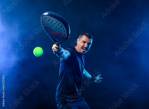 Padel tennis open tour player. Man athlete with paddle tenis racket on black background. Sport concept. Download a high quality photo for sports website. © Mike Orlov