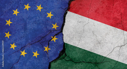 European Union and Hungary flags, concrete wall texture with cracks, grunge background, military conflict concept