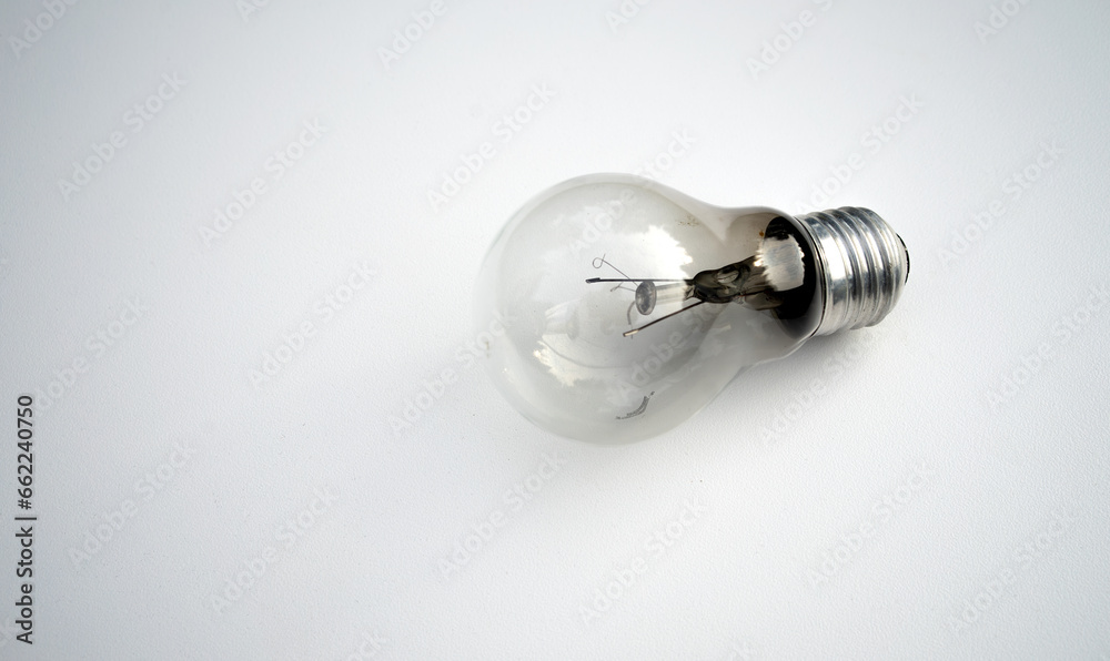 A glass burnt-out incandescent lamp on a white table.An old lighting lamp with a burnt-out spiral. A glass burnt-out incandescent lamp on a white table.An old lighting lamp with a burnt-out spiral.