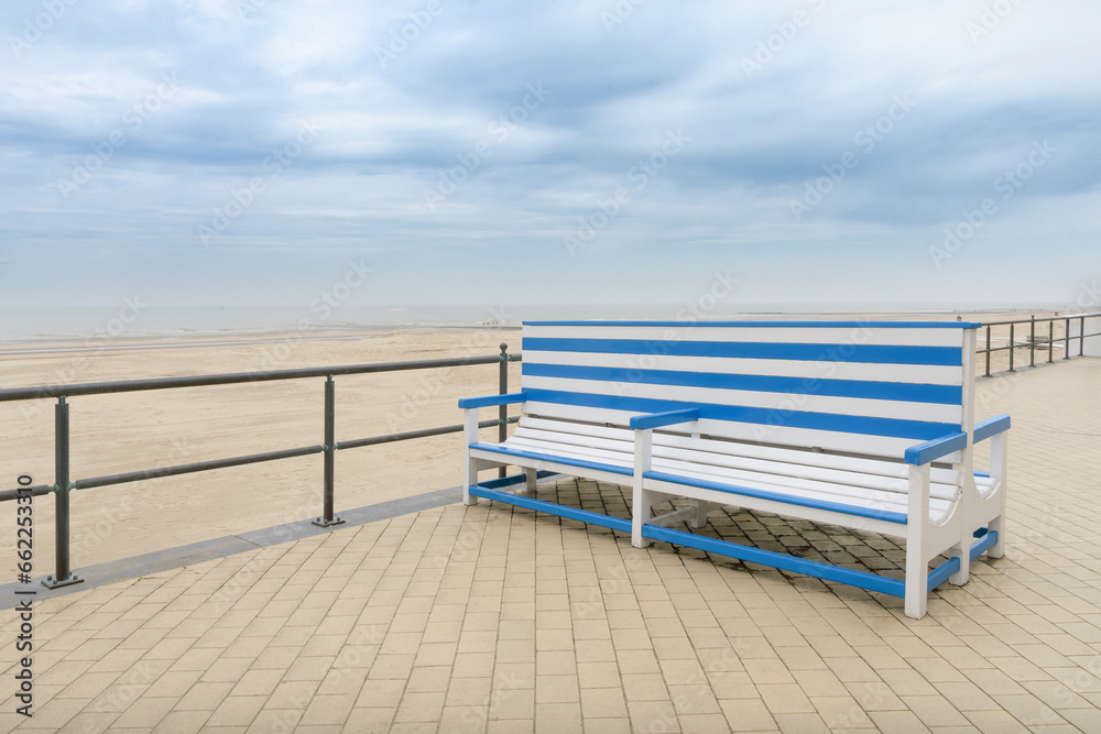 A large beautiful bench on a deserted autumn sea beach at sea. White-blue striped color. Copy space. concept