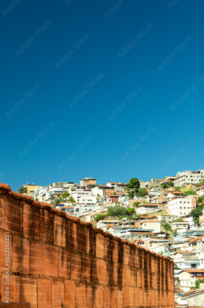 Brick wall. Dark blue sky over houses on top of the hill. Space for advertising. Vertical.