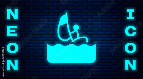 Glowing neon Windsurfing icon isolated on brick wall background. Vector