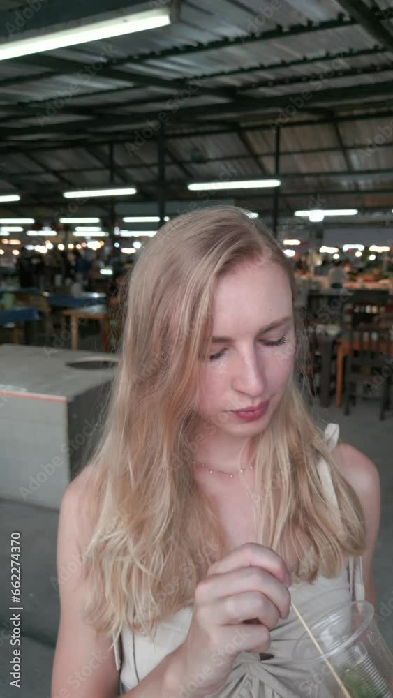 Caucasian woman eats fried insects at a night market in Thailand. Close-up. Caucasian woman eats fried insects at a night market in Thailand. Close-up.