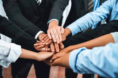 Multiracial business people make synergy hand stack together in meeting room as cooperation or team building for corporate employee in workplace. Meticulous