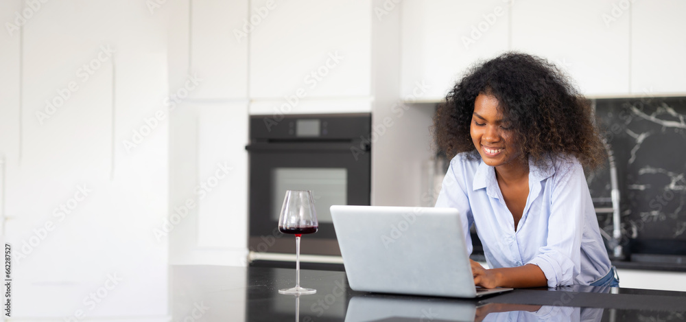 African-American female working at kitchen table in front of generic laptop computer, online banking app for paying bills African-American female working at kitchen table in front of generic laptop computer, online banking app for paying bills