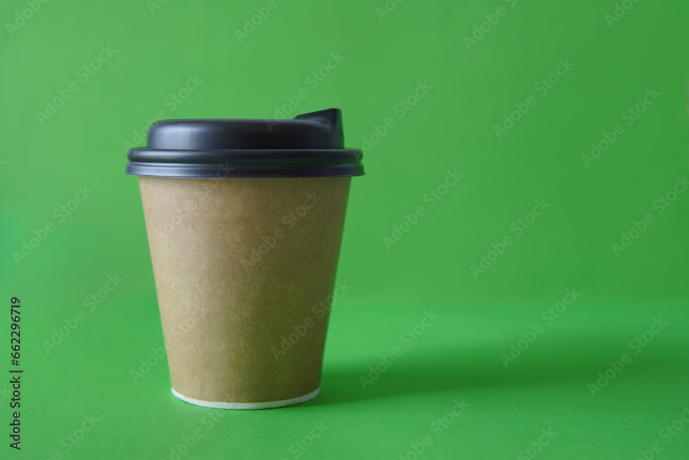 coffee to go in a disposable cup on a green background, you can place text, kraft paper cup. Takeaway paper coffee cup coffee to go in a disposable cup on a green background, you can place text, kraft paper cup. Takeaway paper coffee cup