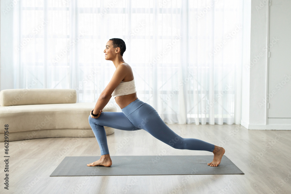 Fototapeta premium Glad young latin lady with short hair in sportswear doing legs stretching workout