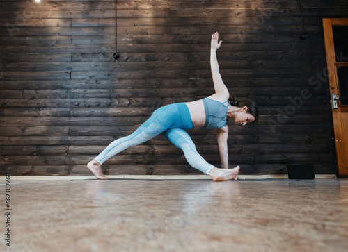 Fototapeta Naklejka Na Ścianę i Meble -  Young woman wearing blue clothes doing yoga exercise  at home