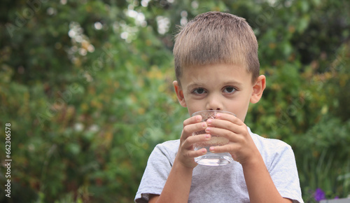 a boy drinks water from a glass in nature. Selective focus