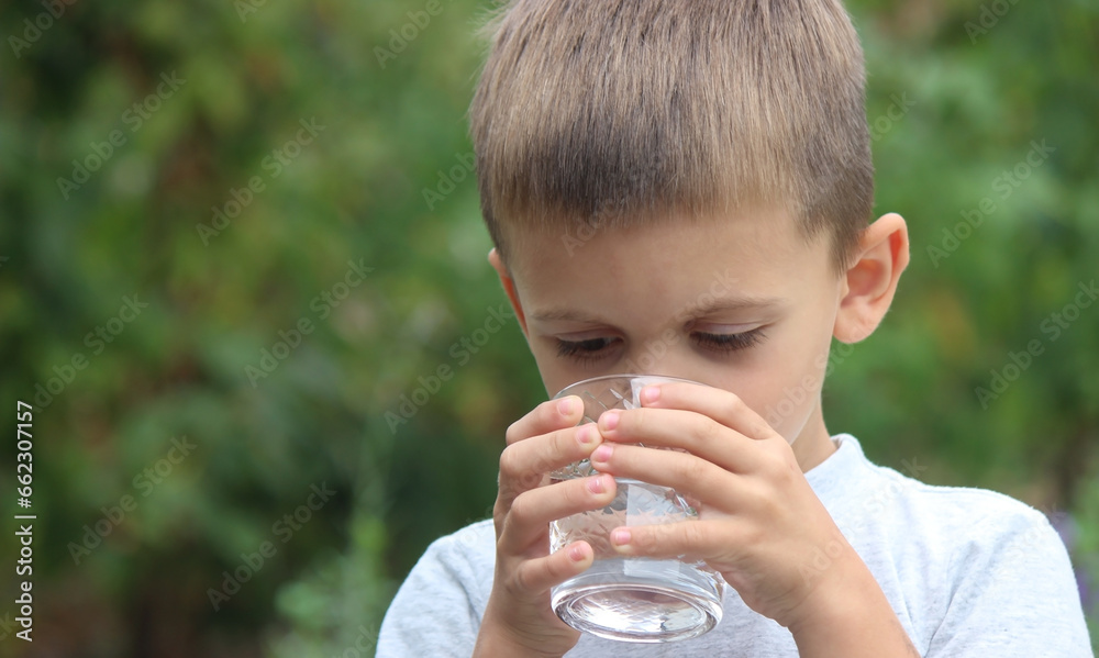 a boy drinks water from a glass in nature. Selective focus a boy drinks water from a glass in nature. Selective focus