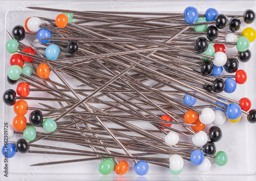 Many multi-colored sewing pins on a white background