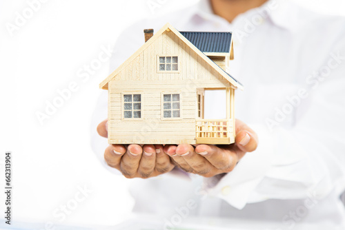 Close-up of woman's hands holding a small model house.