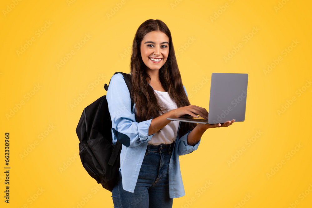 Smiling european teen student woman with backpack, typing on laptop Smiling european teen student woman with backpack, typing on laptop