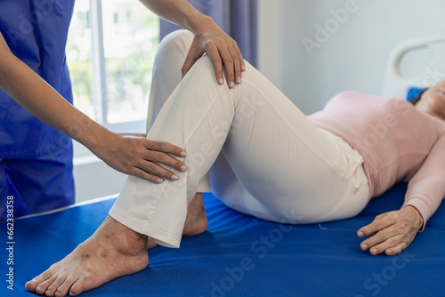 Elderly female patient with Asian female physical therapist holding her arm for physical therapy Rehabilitate weak muscles. A patient appears intent on doing this exercise in a hospital examination ro