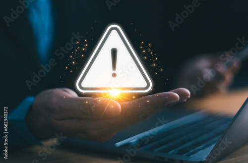Businessman using computer laptop with triangle caution warning sign  available for notification error and maintenance concept  warning risk on device  failure security system online technology 