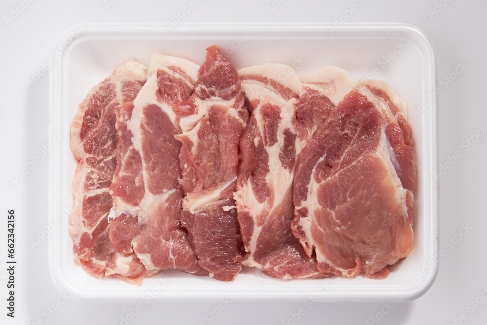 Top view shot of pork shoulder on a white plastic plate on a white background Top view shot of pork shoulder on a white plastic plate on a white background